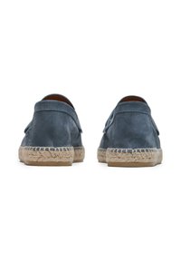 Zapatos de ante azul oscuro con suelas de esparto, que presentan un perfil bajo y un ribete de yute cosido alrededor de los bordes. Suaves y texturizados.