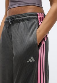 Szürke atlétikai rövidnadrág rózsaszín csíkkal az oldalán, légáteresztő anyagból készült, elasztikus derékrésszel és zsebekkel.