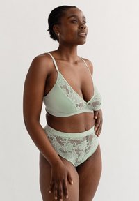 Muntgroen lingerie set met een bralette met kant en bijpassende hooggeplaatste slipjes, beide van zachte, textuurstof.