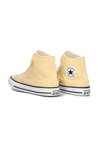 Geel canvas sneakers met hoge schacht, witte veters, zwarte rubberen zolen en een ronde logo patch. Voorzien van contrasterende stiksels en een neuskap.