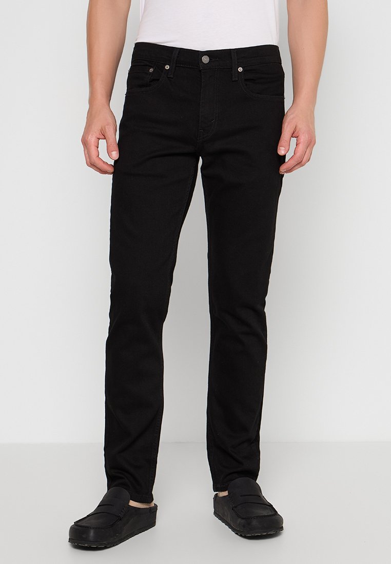 Schwarze Jeans aus Denim mit Slim Fit, Fünf-Taschen-Design und Metallbeschlägen. Passt gut zu einem einfachen weißen T-Shirt und schwarzen Slippern.