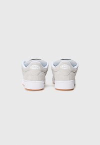 Sive sneakers od sučane kože s bijelim naglascima, podstavljenim ovratnikom oko gležnja i teksturiranom gumenom potplatkom. Sadrže vidljive Reebok oznake na petama.