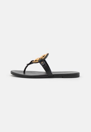 Black flip-flop sandal with a flat sole, featuring a gold chain accent on the strap and a smooth leather texture.
