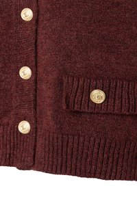Nahaufnahme eines weinroten Strickstoffs mit goldenen Dekoknöpfen an den gerippten Bündchen und einer Taschenklappe.