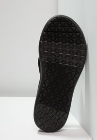 Sort sål med en tekstureret overflade og et geometrisk mønster, lavet af gummi, som viser et fladt, bredt design.