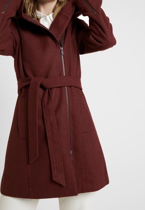 Abrigo burdeos con capucha, cierre frontal de cremallera y cinturón. Hecho de tela texturizada, con dos bolsillos laterales y un corte entallado.