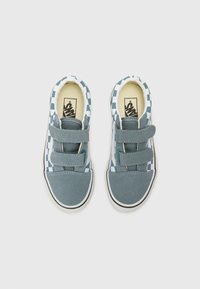 Baskets en toile bleue avec un motif à carreaux, deux bandes Velcro et une semelle en caoutchouc blanche. La doublure intérieure est de couleur crème.