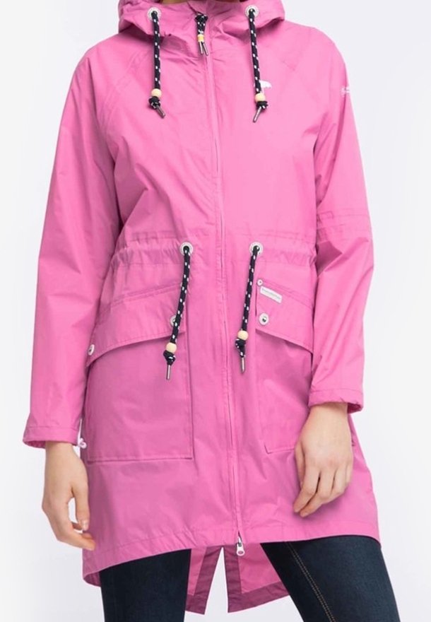 Vaaleanpunainen vedenpitävä takki, jossa on vetoketjukiinnitys, säädettävä huppu, kaksi etutaskua ja kontrastiväriset tummansiniset narut. Sileä, kevyt kangas.