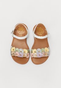 Sandales en cuir blanc avec une bride florale dans des couleurs pastel, des accents métalliques et une semelle marron. Logo de la marque visible sur la semelle intérieure.