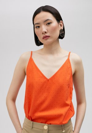 Top sin mangas naranja con escote en V, con lunares texturizados y un pequeño detalle bordado en el pecho. Tejido suave, corte holgado.