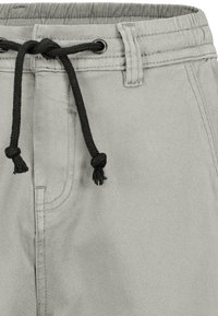 Helle graue Shorts mit einem elastischen Bund, der mit einem schwarzen Kordelzug zusammengezogen wird; verfügt über Taschen und eine glatte Stofftextur.
