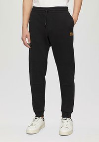 Schwarze Jogginghose aus Baumwollmischung mit elastischem Bund und Kordelzug. Verfügt über seitliche Taschen und gerippte Bündchen. Kleines Logo-Detail.