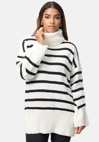 Pull rayé blanc et noir, doté d'un col roulé haut, de poignets côtes et d'une coupe ample avec une longueur de dos plus élevée. Texture en maille.