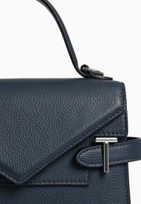 Dunkelblaue Lederhandtasche mit strukturiertem Finish, eckigem Klappendesign, Metallbeschlägen und einem oberen Tragegriff.