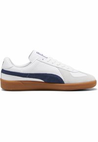Weißer Sneaker mit einem marineblauen Wildlederstreifen, Obermaterial aus Leder und Wildleder, runde Zehenform, weiße Schnürsenkel und einer Sohle aus Gummi. Minimale Markenanbringung auf der Zunge.