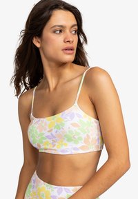 Bralet s kvetinovým vzorom v pastelových farbách (zelená, žltá, ružová, fialová), tenké ramienka a mäkká tkanina s hladkým povrchom.