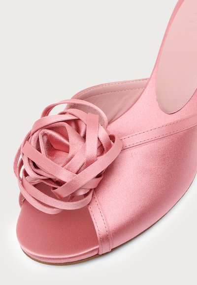 Mule à bout ouvert en satin rose avec une rosette décorative en ruban de satin sur le dessus avant.