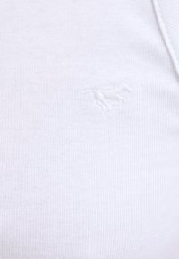 Tissu tricoté blanc avec un contour brodé subtil d’un cheval au galop en fil blanc assorti.
