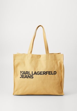 Sac fourre-tout en toile beige avec deux poignées et texte noir gras "KARL LAGERFELD JEANS" à l'avant sur un fond uni.