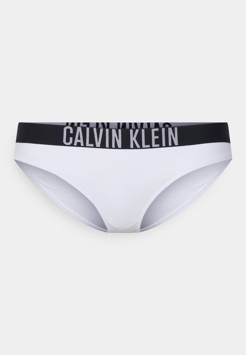 Valge bikiinipõhi, mis on valmistatud siledast kangast, musta elastse vööga, millel on "CALVIN KLEIN" logo. Klassikaline lõige, minimalisti kattega.