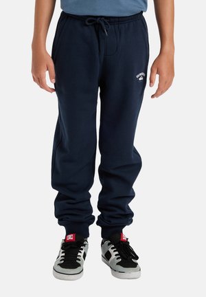 Navy blue sweatpants made of soft cotton, featuring an elastic waistband with drawstring, cuffed ankles, and a small logo on the left thigh.