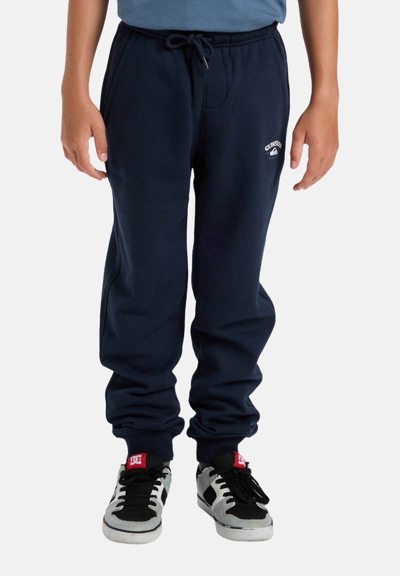 Navyblaue Sweatpants aus weichem Baumwollmaterial, mit einem elastischen Bund und Kordelzug, gerippten Knöcheln und einem kleinen Logo am linken Oberschenkel.
