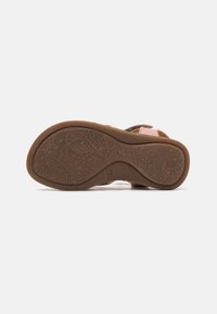 Brun gummisåle med intrikate vinhmønstre, med en rosa tekstilstropp og et slitesterkt design som passer til hverdagsbruk.
