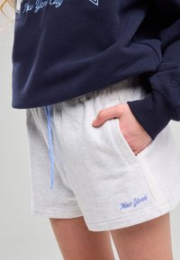 Sweatshirt bleu marine avec le texte "New York City", associé à un short gris clair avec une poche latérale et un cordon de serrage bleu, portant une broderie "New York".