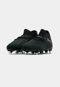 Botas de fútbol negras con parte superior texturizada, acentos verdes y cuello tipo calcetín. Suela con tacos para tracción en superficies de hierba.