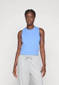 Ljusblå ärmlös crop top med rund hals och subtil logotyp, kombinerad med grå sweatpants med justerbar midja och logotypdetalj.