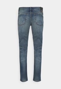 Slim fit blå denimjeans med blekt tvätt, fem fickor och kontrasterande sömmar på bakfickorna. Inga synliga slitningar eller utsmyckningar.