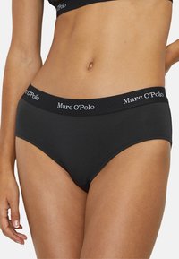 Culottes pour femmes noires en coton avec une taille élastique douce portant le texte "Marc O'Polo" en blanc. Tissu en coton lisse et design à coupe classique.
