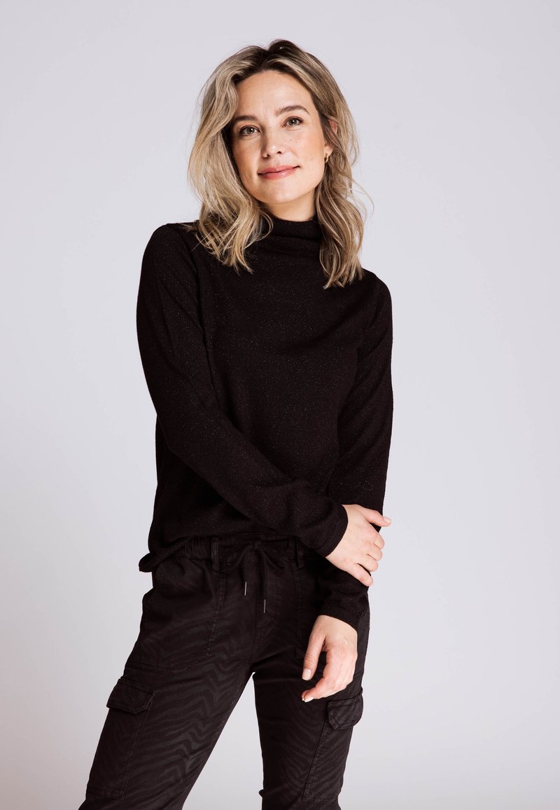 Black turtleneck top with a subtle sparkle texture, paired with black cargo pants featuring a textured pattern and elastic waistband.