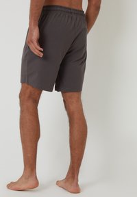 Pantaloni corti in cotone grigi con un elastico in vita, dotati di una tasca posteriore e una vestibilità comoda. Texture liscia con un design semplice.