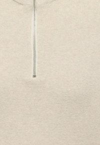 Svetle béžový svetr na zip s jemnou strukturou, s vertikálním zipem na krku a žebrovaným pleteným vzorem.