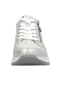 Baskets blanches avec des accents argentés, présentant un dessus texturé, des lacets proéminents et une fermeture éclair sur le côté pour un accès facile. Conception à semelle plate.