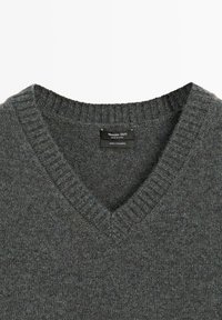 Dark gray cashmere v-neck sweater. Features ribbed neckline and texture, with a label reading "Massimo Dutti" and "100% Cashmere."