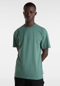 Hellgrünes Baumwoll-T-Shirt mit Rundhalsausschnitt, kurzen Ärmeln und geradem Saum. Verfügt über ein kleines Etikett in der unteren linken Ecke.
