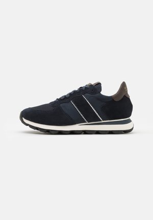 Sneaker navy con upper in suede e mesh, accenti a strisce bianche, colletto imbottito e soletta rotonda in gomma. Presenta una chiusura con lacci.