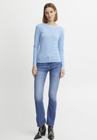 Ljusblå långärmad topp i mjukt tyg, kombinerad med tajta jeans i medium tvätt. Avslutad med svarta klackboots.
