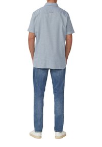 Camicia a maniche corte, a righe blu chiaro, con colletto e spalle rinforzate, abbinata a jeans blu e sneakers bianche. Design casual.