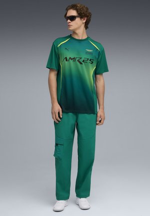 Groene gradient sportshirt met zwarte tekst, gecombineerd met bijpassende groene cargobroek. De outfit heeft korte mouwen en is gemaakt van lichtgewicht materiaal.