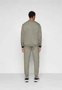 Sivi dukserica i trenerke izrađeni od mekanog materijala, s okruglim izrezom, rebrastim manžetama i usklađenim patikama s crnim detaljima.