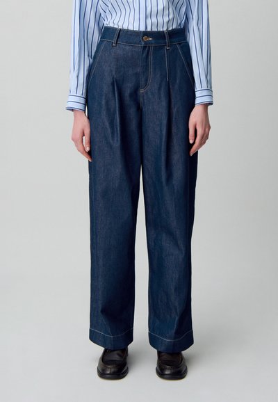 Pantalones de mezclilla oscura de pierna ancha con talle alto, que presentan costuras en contraste y un detalle de botón en la cintura.