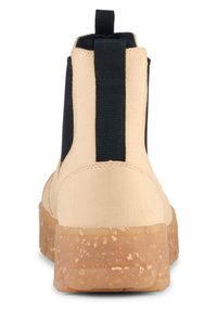 Beige ankelsko med svarta elastiska sidopaneler, strukturerad form, texturerad gummisula och en dragflik bak för enkel påtagning.
