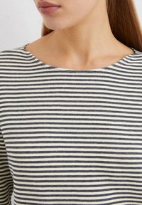 Striped top featuring alternating navy and cream horizontal stripes, with a wide neckline and soft, textured fabric.