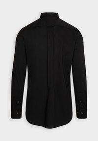 Chemise noire à manches longues vue de dos avec poignets boutonnés et col droit sur un fond uni.