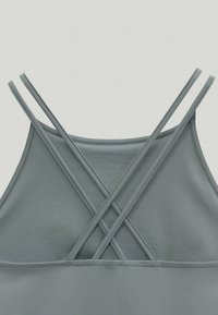 Jasnoszary top na ramiączkach o gładkiej fakturze z krzyżującym się wzorem na plecach, wyposażony w cienkie, regulowane ramiączka.