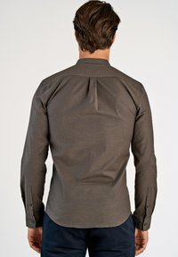 Ciemnobrązowa koszula zapinana z gładką fakturą, długimi rękawami i plisą z tyłu. Zawiera czarne guziki przy mankietach.