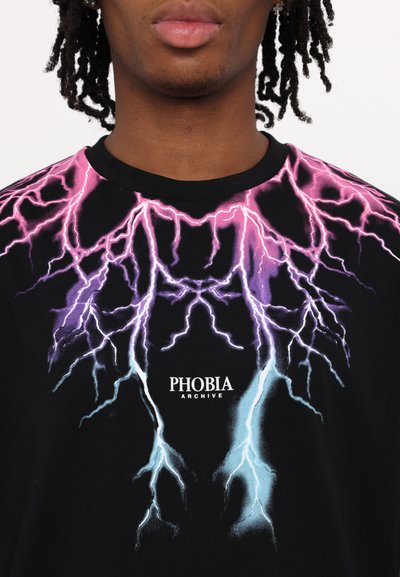 T-shirt nera con una grafica colorata di un fulmine nei colori rosa, viola e blu, con il testo "PHOBIA ARCHIVE" al centro.
